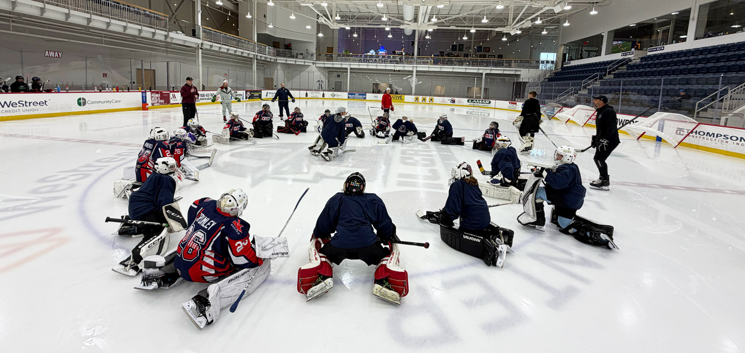 Young hockey goalies circled at center ice during a Keserich Goaltending summer camp