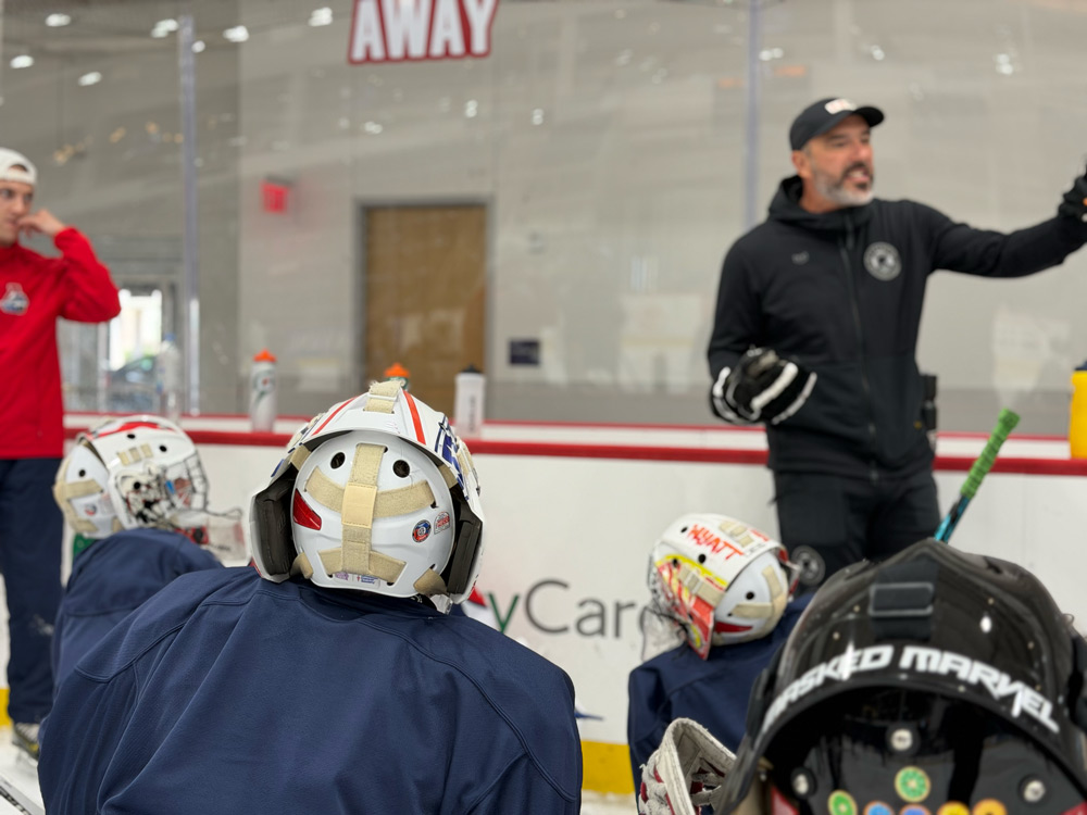 Coach demonstrating positioning to seated goalies