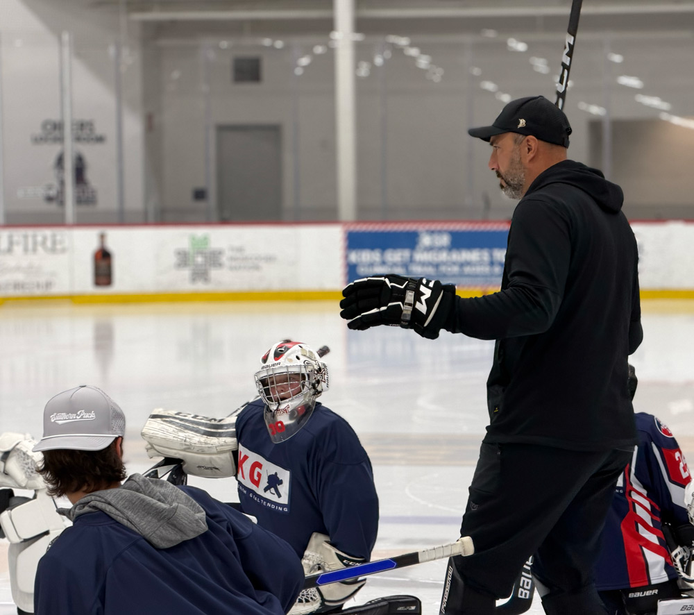 Ian Keserich giving one-on-one instruction to a masked goalie