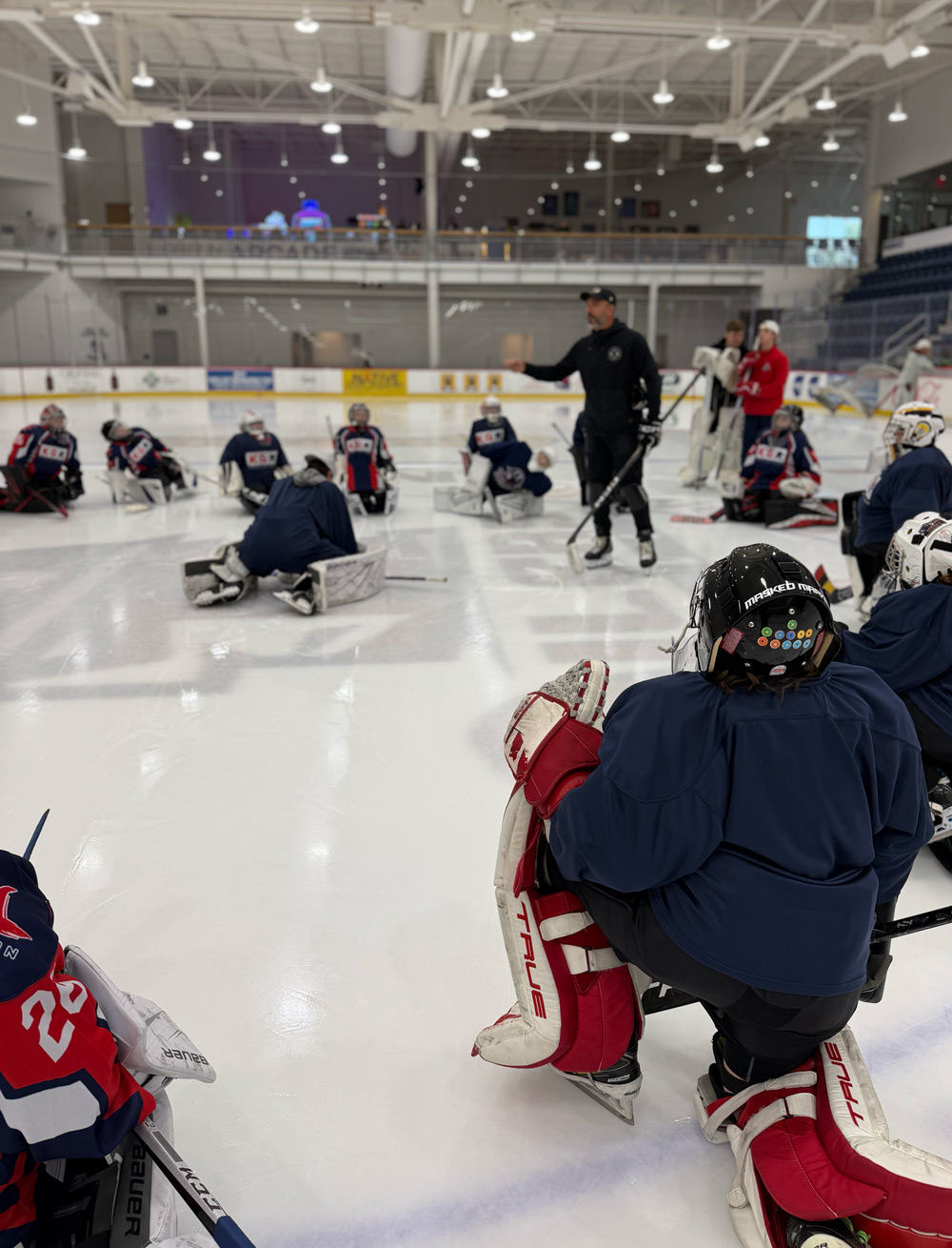 Camp goalies watching instruction from the ice